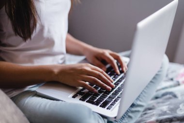 Genç kız yatak odasında dizüstü bilgisayar kullanarak