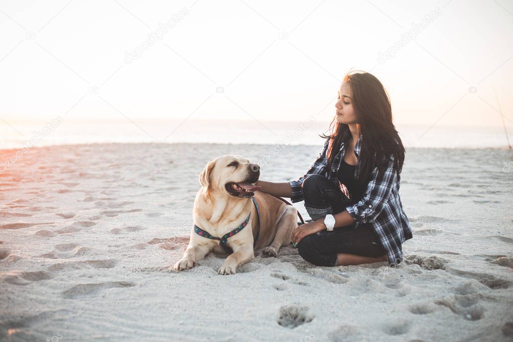 Girl sitting with dog on beach