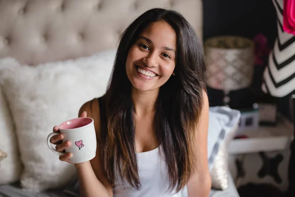 Gadis memegang secangkir kopi di tempat tidur — Stok Foto
