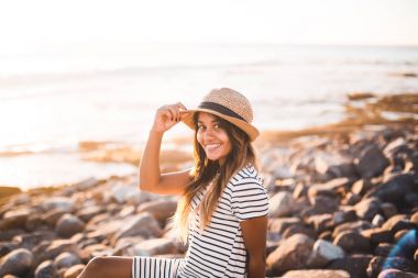 Plaj kayalar üzerine oturan genç kadın