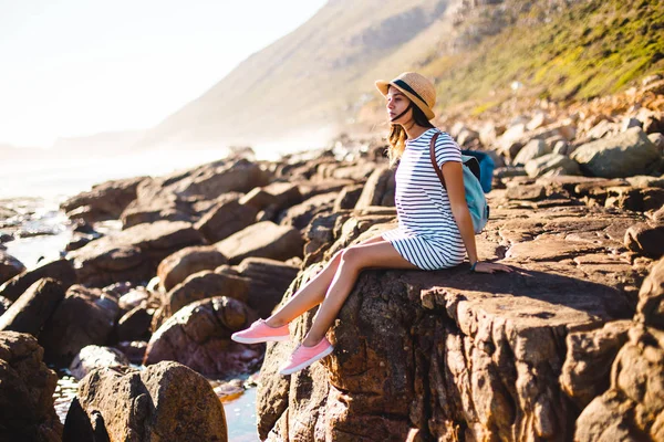 Jonge vrouw zittend op strand rotsen — Stockfoto