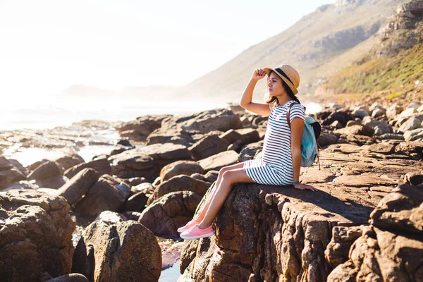 Молода жінка сидить на пляжних скелях — стокове фото
