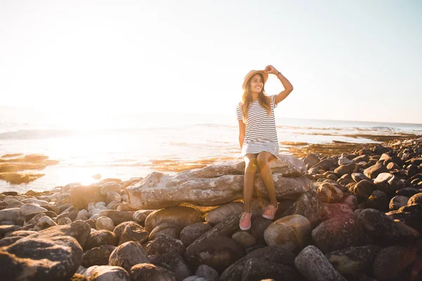 Mujer joven sentada en rocas de playa —  Fotos de Stock