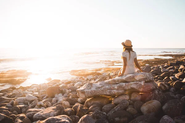 Jonge vrouw zittend op strand rotsen — Stockfoto