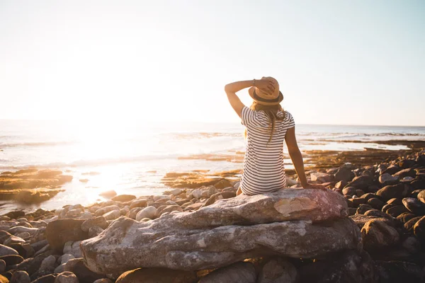 Jeune femme assise sur des rochers de plage — Photo