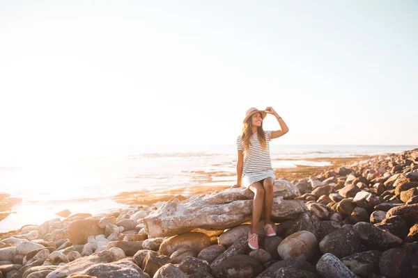 Mujer joven sentada en rocas de playa — Foto de Stock