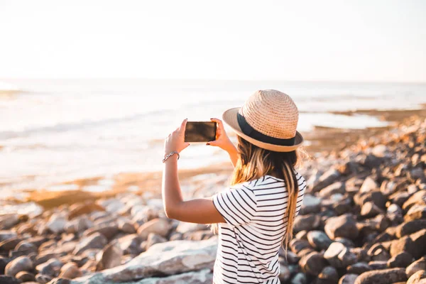 Mujer joven tomando fotos en la playa —  Fotos de Stock