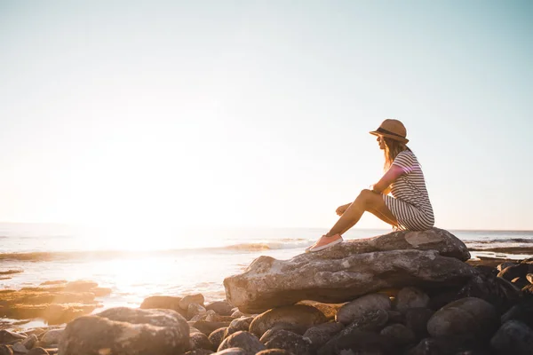 Молода жінка сидить на пляжних скелях Стокове Фото