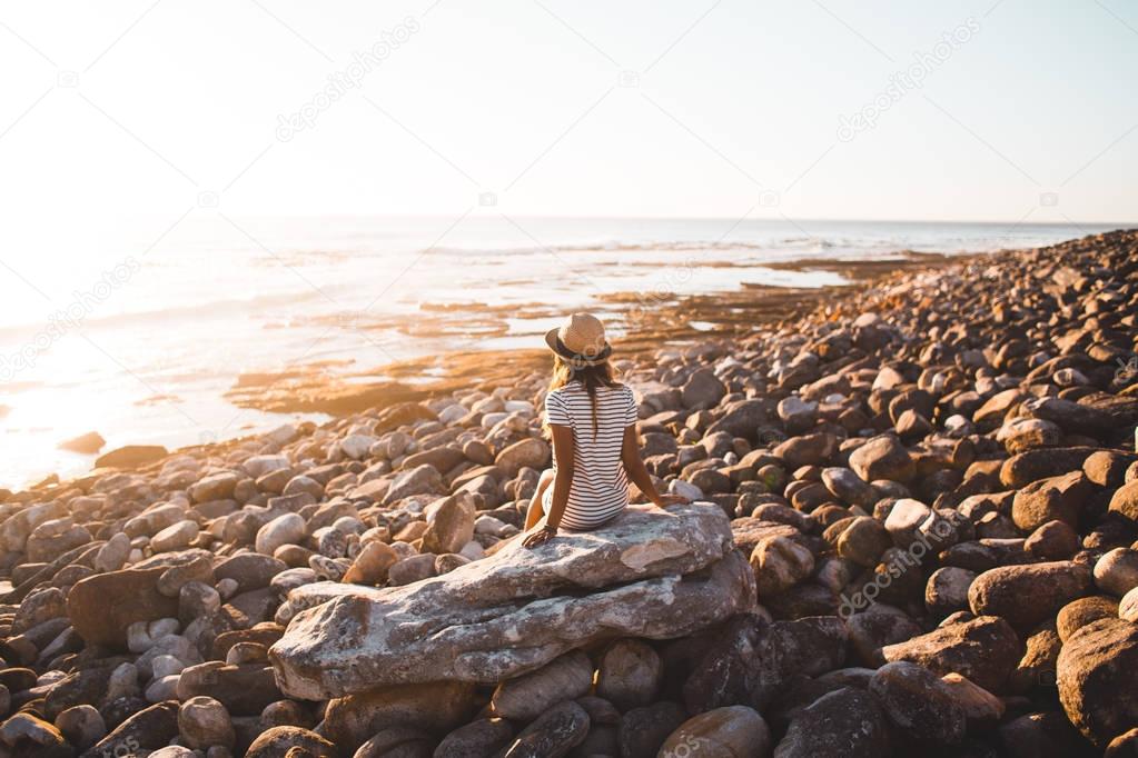 Young woman sitting on beach rocks