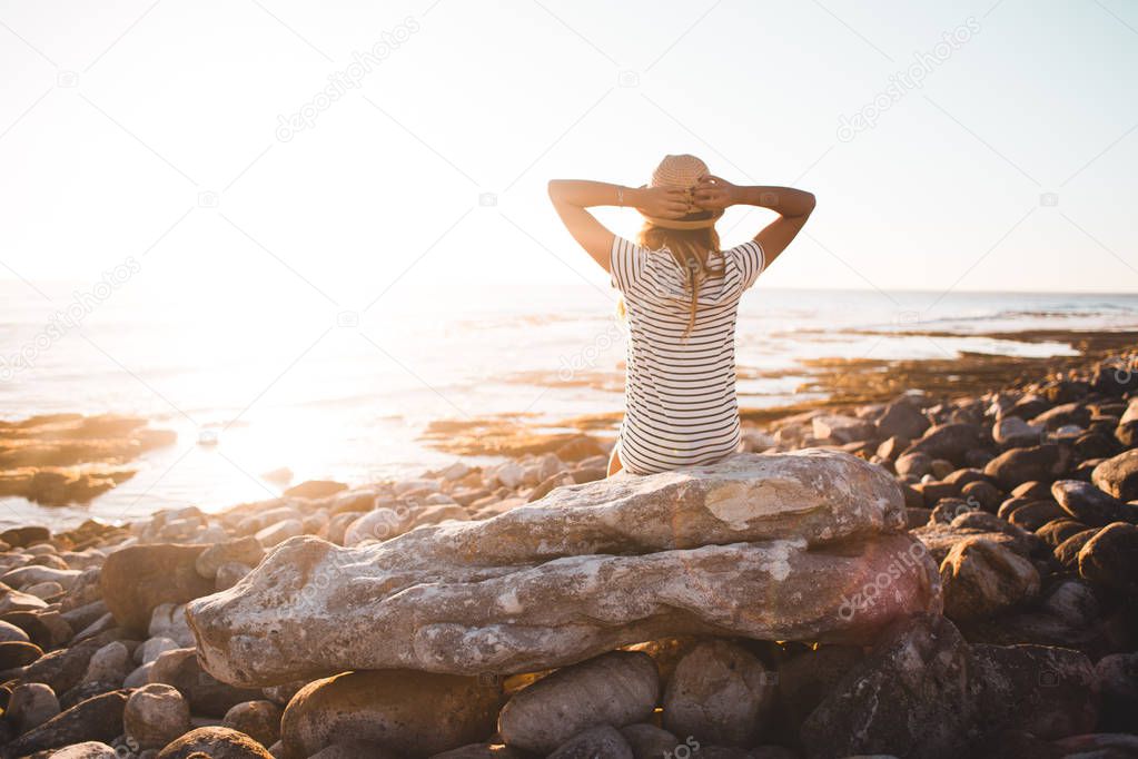 Young woman sitting on beach rocks