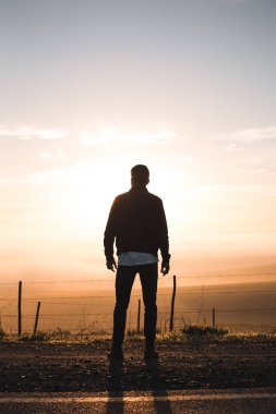 Yolda duran ve gündoğumu izlerken adam