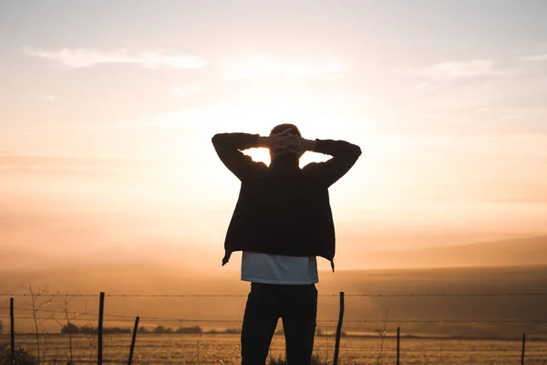 Uomo con le braccia alzate a guardare l'alba — Foto Stock