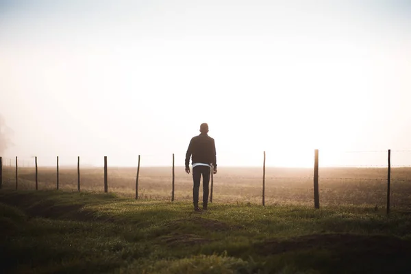 Hombre de pie en el camino y mirando el amanecer —  Fotos de Stock