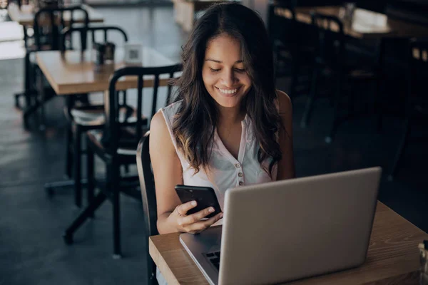 Gadis Ras Campuran Muda Tersenyum Dan Menggunakan Smartphone Sambil Duduk — Stok Foto