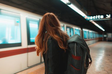 Tren istasyonunda dikilen ve gelen trene bakan kadının dikiz görüntüsü.