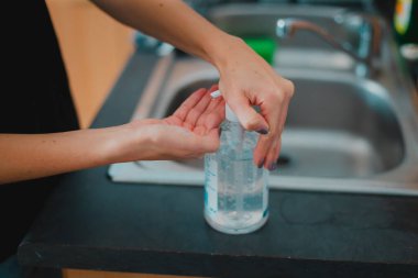 Delikanlı dezenfektan kullanarak el yıkıyor.