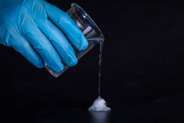 Kimyasal deneyler. Sıvı camdan siyah masaya dökülür ve hemen donar..