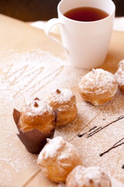 Ambalaj için kahverengi kağıt üzerinde çay ile Profiteroles, krem şanti ile kek.