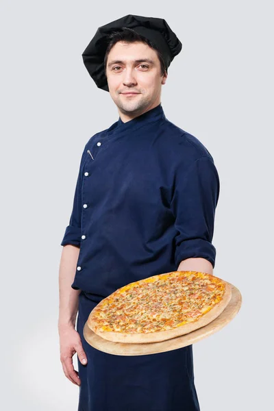 Ung, lykkelig mannlig kokk presenterer varm pizza på kjøkkenet – stockfoto