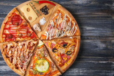 Dilim pizza olmadan tek parça, farklı tatlar ile ahşap bir masaya kesilmiş