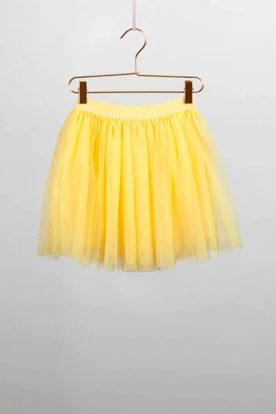 Věšák na sukně žlutá adoptovaných na šedém pozadí — Stock fotografie