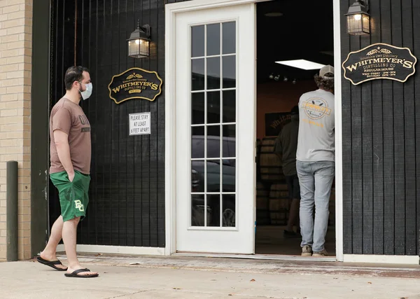 Houston, TX - 31 Mart 2020: Koruma maskesi takan bir adam Whitmeyer Damıtma Şirketi 'nden bedava el dezenfektanı almaya hazırlanıyor..