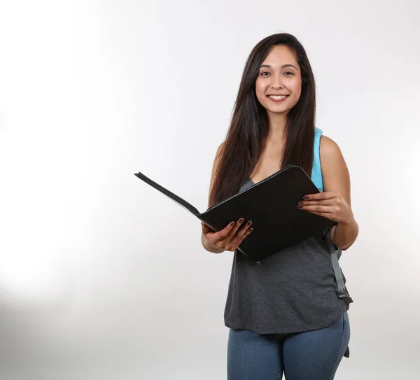 Yedek lastik takan genç bir kız öğrenci gülümserken portföyünü tutuyor..