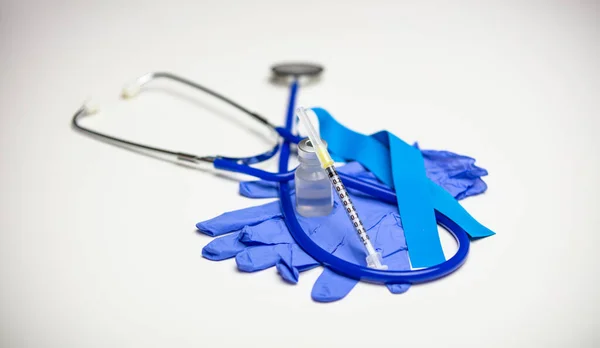 Boş bir şırınga dolu bir şişenin üzerinde duruyor. Arka planda eldiven, turnike ve steteskop var..