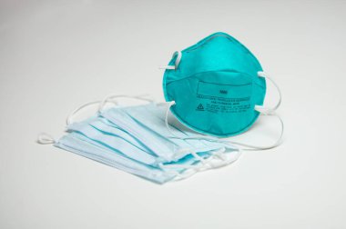 A closeup of an assortment of protective face masks. One N95 and three surgical masks. clipart