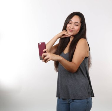 Gözlüklü ve gri tişörtlü çekici bir Latin fotoğraf çekmek için cep telefonunu kaldırırken gülümsüyor..