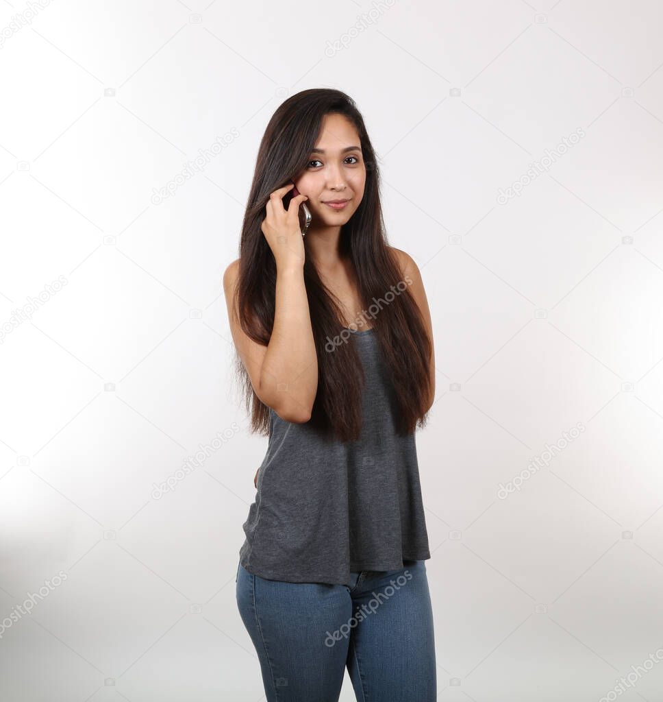 A young attractive hispanic female holds patiently on the phone.
