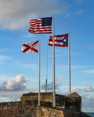 San Juan, Porto Riko 'daki El Morro' da dalgalanan üç bayrak. Amerikan, Porto Rikolu ve Burgundy bayrakları Haçı.