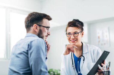 Doktor ve hasta doktorun ofisinde oturuyor.