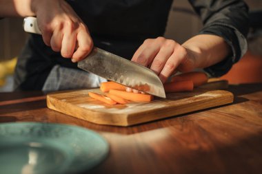 Tahtada havuç doğrayan kadın şef.