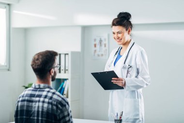 Doktor ve hasta doktorun ofisinde oturuyor.