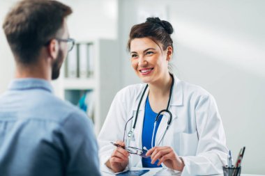 Doktor ve hasta doktorun ofisinde oturuyor.