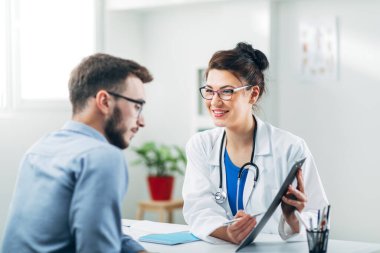 Doktor ve hasta doktorun ofisinde oturuyor.