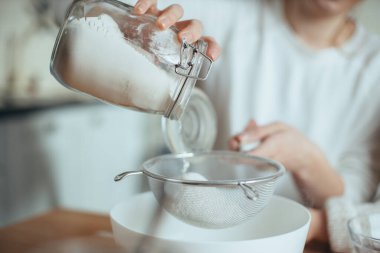 Close up shot of a chef poring flour through a sieve