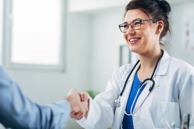 Doktor ve hasta doktorun ofisinde el sıkışıyor.