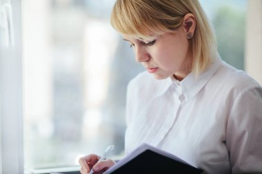 Ofiste çalışan, not defterinde yazan bir kadın.