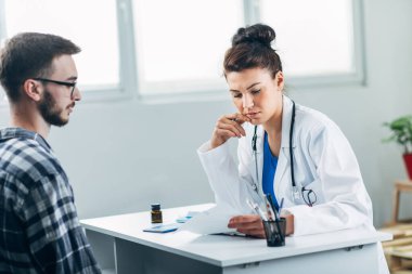 Doktor ve hasta doktorun ofisinde oturuyor.