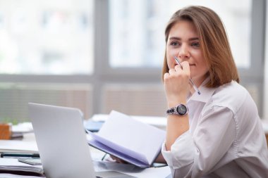 Ofiste çalışan bir kadın, bir belge okuyor.