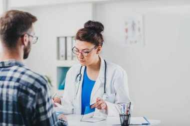 Doktor ve hasta doktorun ofisinde oturuyor.