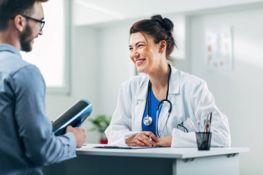 Doktor ve hasta doktorun ofisinde oturuyor.