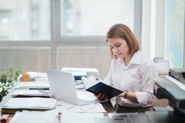 Ofiste çalışan bir kadın, bir belge okuyor.