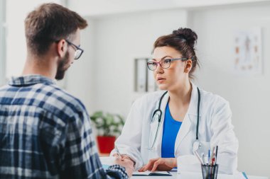 Doktor ve hasta doktorun ofisinde oturuyor.