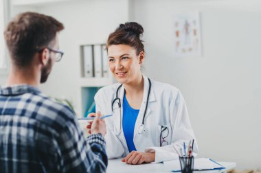 Doktor ve hasta doktorun ofisinde oturuyor.