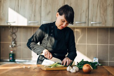 Ahşap bir tahtada çiğ sebze doğrayan kadın şef.