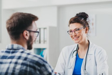 Doktor ve hasta doktorun ofisinde oturuyor.