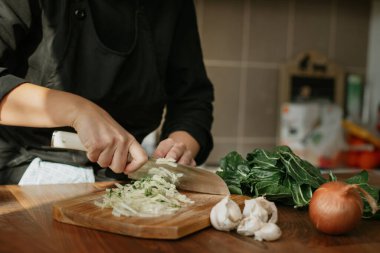 Ahşap bir tahtada çiğ sebze doğrayan kadın şef.